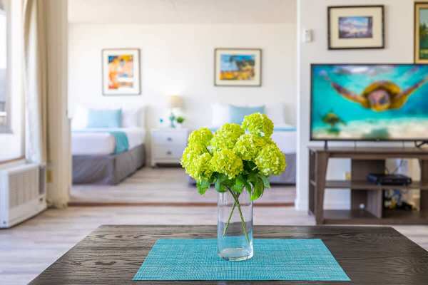Modern living space with fresh floral centerpiece and twin beds in the background.