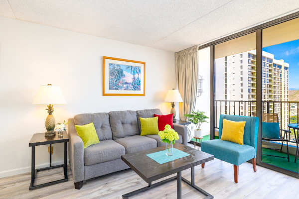 Bright living room with colorful accents and balcony views of nearby buildings.