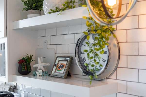 Modern kitchen shelf with decorative plants and a vintage-style clock.