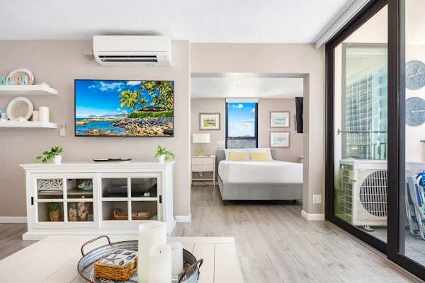 Modern living area with a view into the bedroom and access to a balcony.