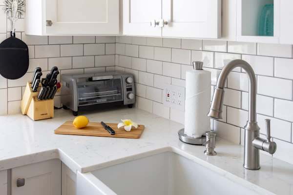 Modern kitchen corner with stainless steel faucet and white subway tile backsplash