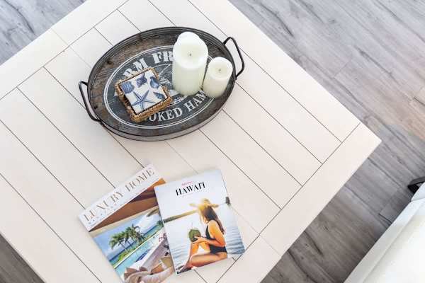 white coffee table with decorative tray and magazines on wood flooring