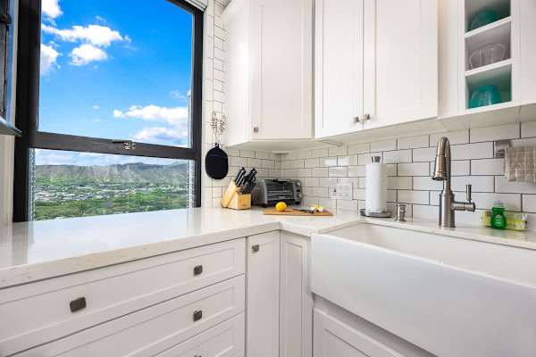 modern kitchen corner with white cabinetry and a view of the mountains through the window