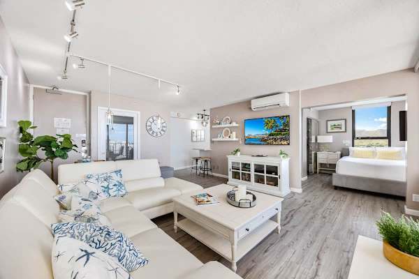 Bright living area with a white sectional sofa and a view into the bedroom.