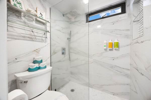 Modern bathroom with marble walls and a walk-in glass shower.