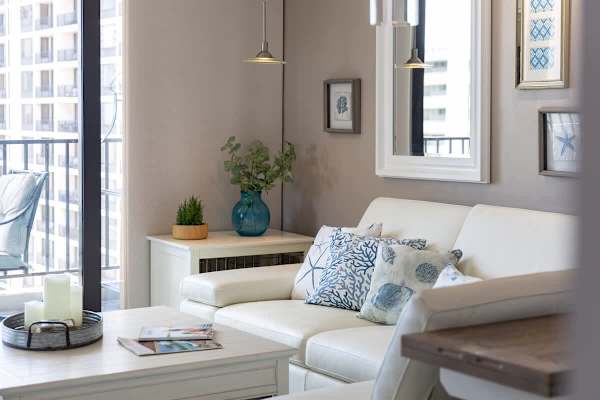 Relax in this modern living room with coastal-themed decor and natural light from the balcony.