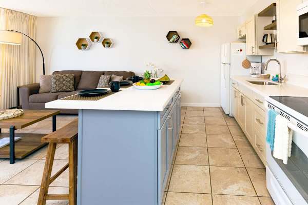 Modern kitchen with a blue island and open living area for relaxing and dining.