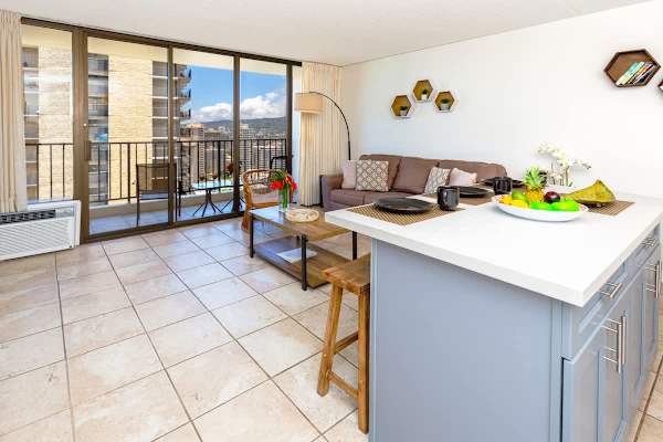 Bright living area with a balcony offering city views and a modern kitchen island.