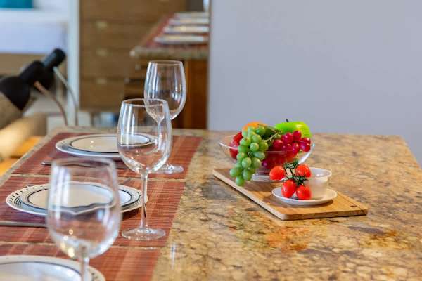 Dining table beautifully set w/ glassware & fresh touches for a memorable meal.
