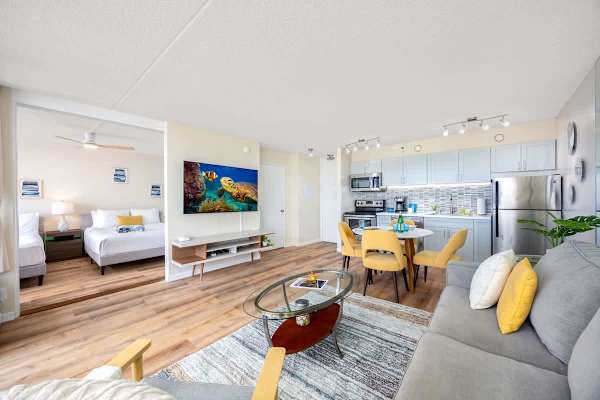 Bright living area with modern kitchen and dining space featuring yellow chairs.