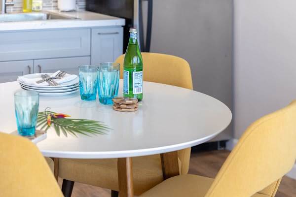 Modern dining table with yellow chairs and blue glassware for a vibrant meal setting.
