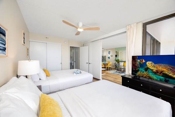 Bright bedroom with two beds and a view into the living area