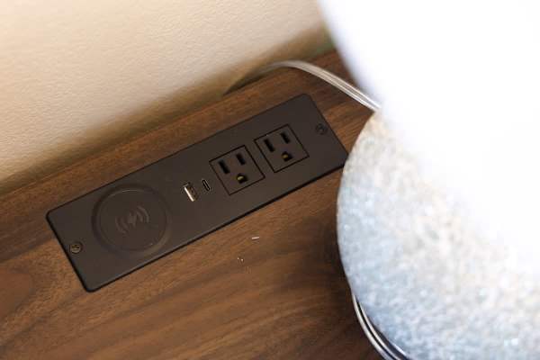 Built-in charging station with power outlets and USB ports on a wooden surface.