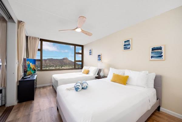 Bright bedroom with two beds and a view of diamond head mountain.