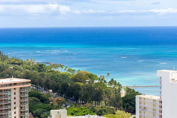 Ocean view with lush greenery and nearby beachfront buildings
