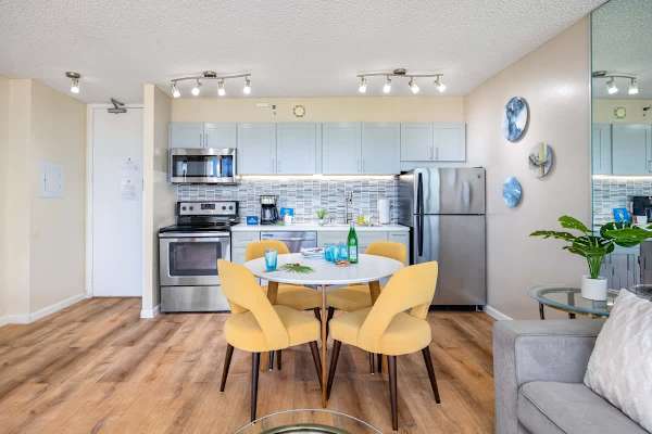 Modern kitchen and dining area with stainless steel appliances and yellow chairs.