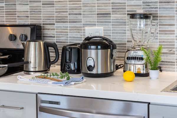 Modern kitchen countertop with essential appliances including a kettle, toaster, rice cooker, and blender.