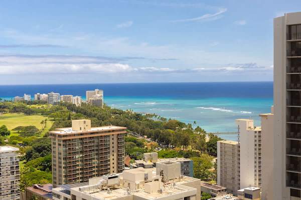 Ocean view from a high-rise balcony overlooking the coastline and cityscape.