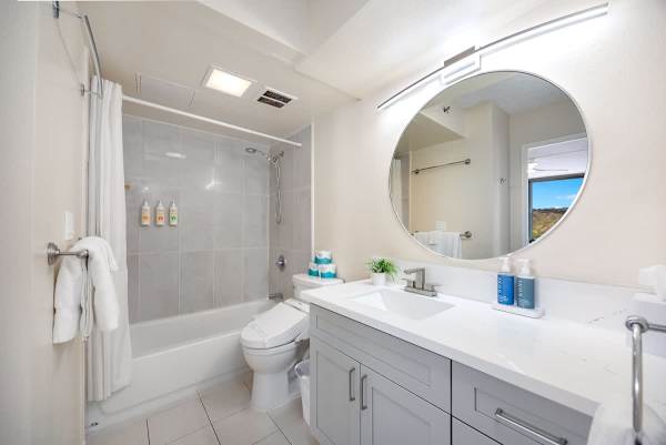 Modern bathroom with a large round mirror and a bathtub with shower.