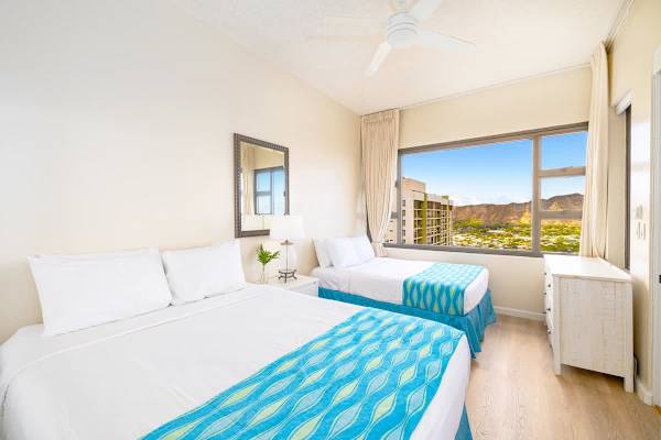 bright bedroom with two beds and a large window offering mountain views