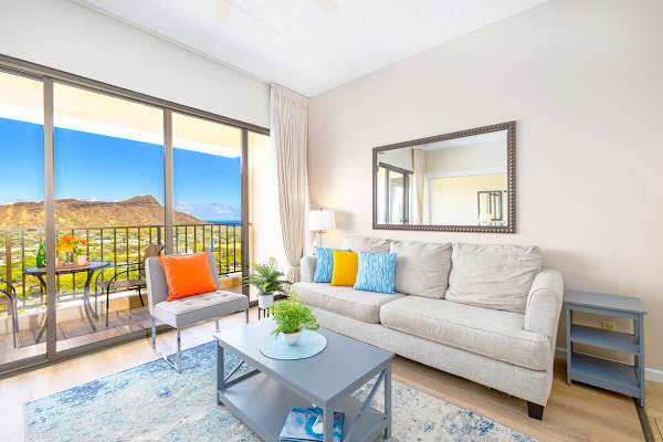 Bright living room with colorful accents and a balcony overlooking mountain views.