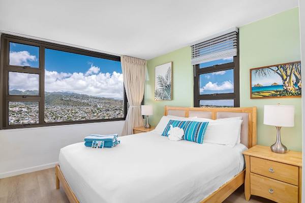 Bright bedroom with large windows offering panoramic city and mountain views.
