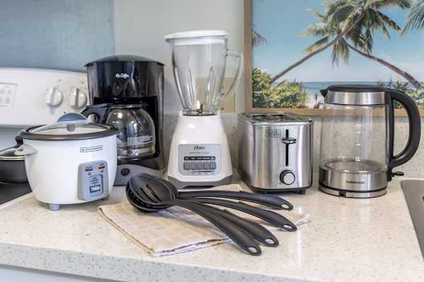 Kitchen countertop with essential appliances including a coffee maker, blender, toaster, and electric kettle for convenient meal preparation.