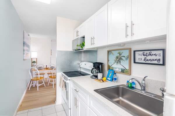 Compact kitchen with white cabinetry and a view into the dining area.
