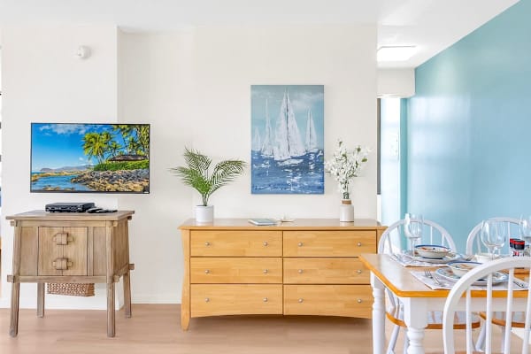 Bright dining area with coastal artwork and a flat-screen television.
