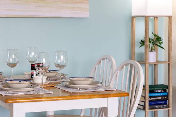 dining table set for four in a cozy, light-filled room with a wooden floor lamp and decorative plants