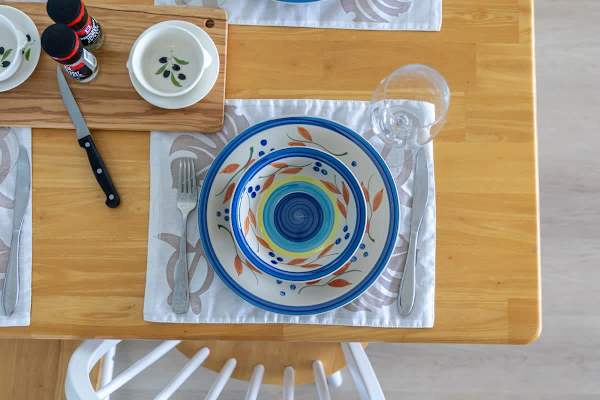 dining table set with colorful ceramic plates and glassware for a casual meal