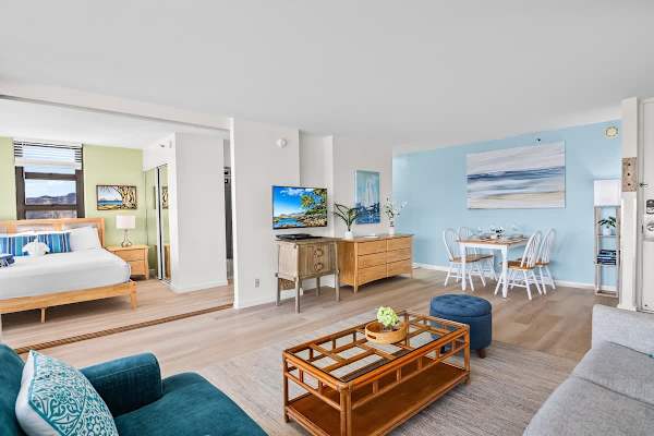 Bright living and dining area with coastal-inspired decor and a separate bedroom space.