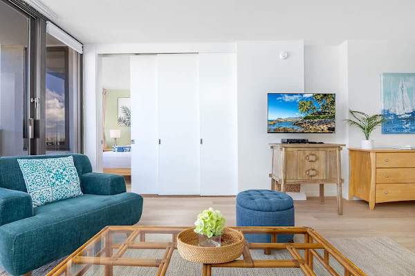 Bright living area with teal sofa and natural wood accents for a relaxing stay.