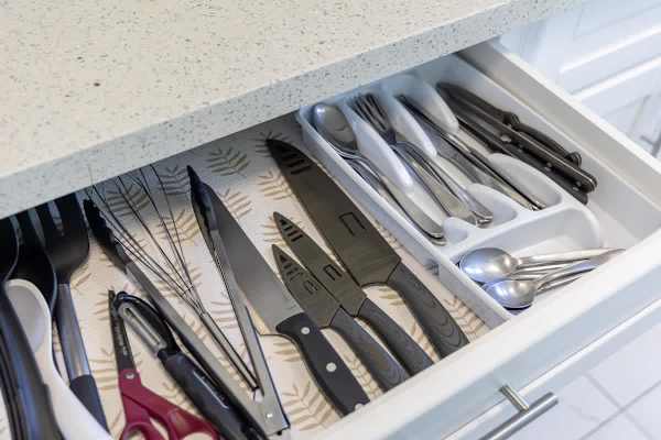 Organized kitchen drawer with knives, utensils, and cutlery for convenient meal preparation.