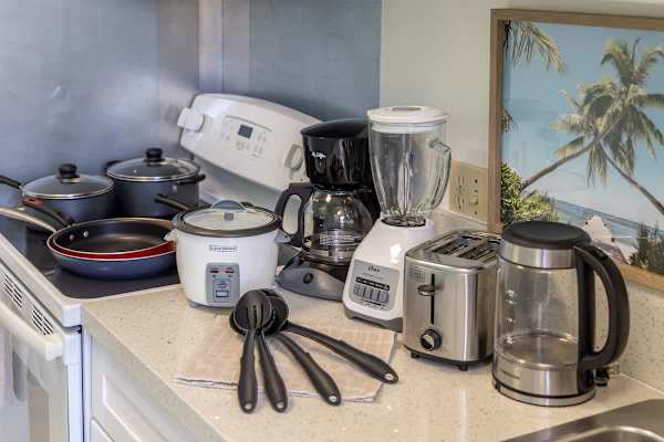 Kitchen countertop with essential appliances including a coffee maker, blender, toaster, and cookware for convenient meal preparation.