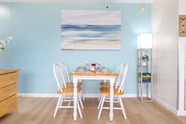 Cozy dining area with a wooden table set for four against a calming blue wall.