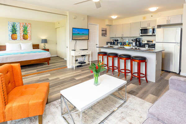 Living room with open kitchen, countertop-bar with 4 barstools, pull out sofa, chair, coffee table and 43" TV 