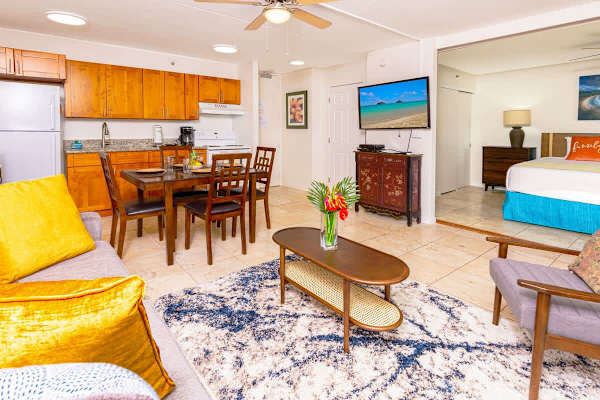 Open kitchen with a dining table and chairs for 4 people, pull-out sleeper sofa, chair, coffee table, and bathroom access