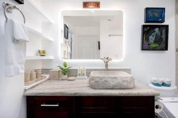 Enjoy modern convenience and distinctive style with the illuminated mirror and custom stone sink.