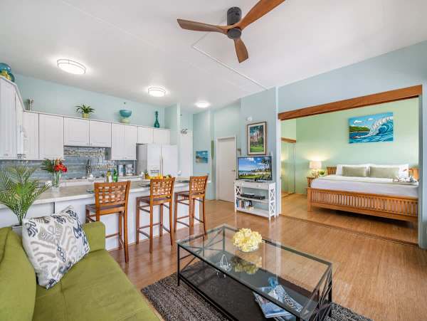 Living room with ceiling fan, smart TV with cable box, kitchen and counter top with 3 barstools