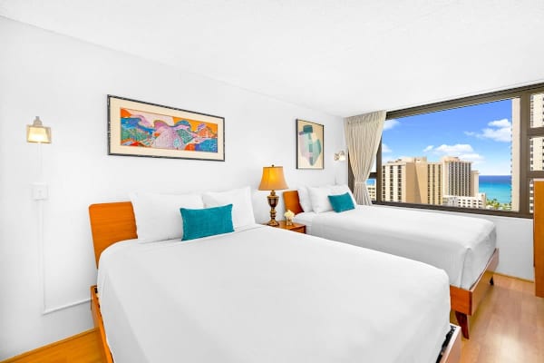 The bedroom includes two queen beds and a stunning ocean view.