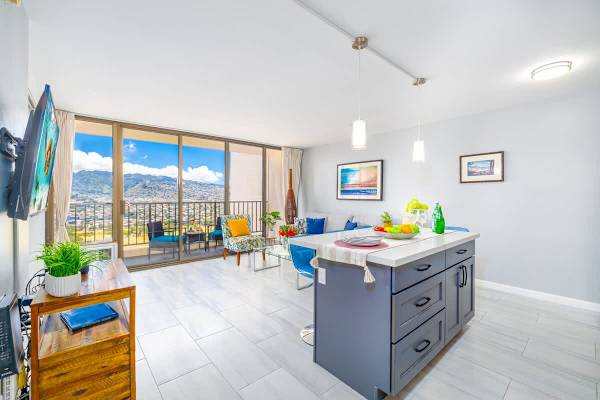 Bright living area with modern kitchen island and balcony overlooking mountain views