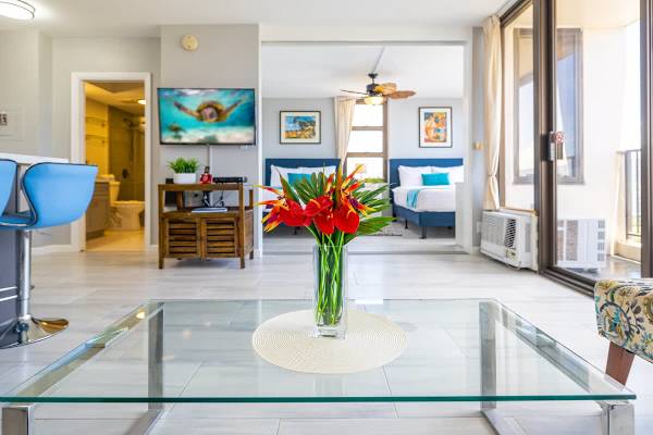 Modern living area with a glass coffee table and vibrant floral centerpiece.