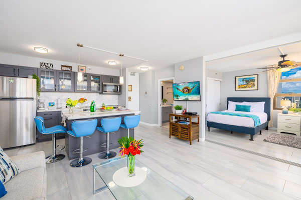 Modern kitchen and living area with blue bar stools and a bright bedroom with city views.