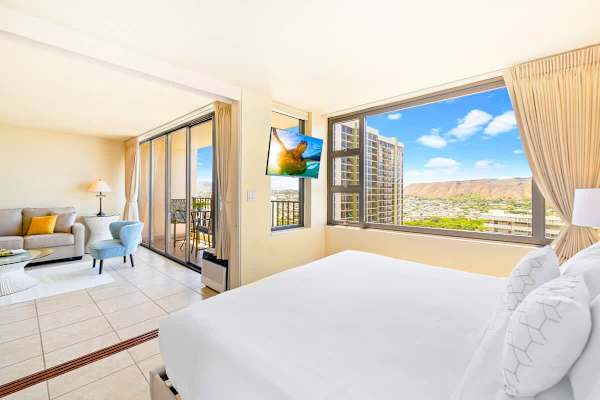 Bright modern suite with city and mountain views and a balcony seating area.