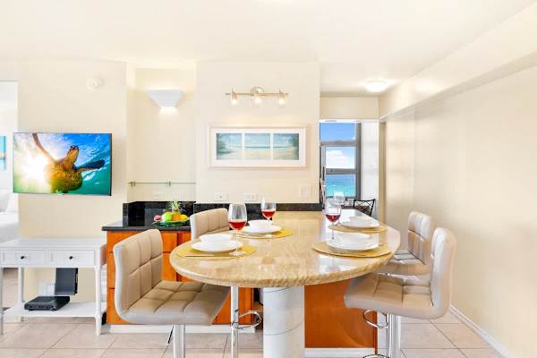 Modern dining area with a marble island and ocean view in the background.