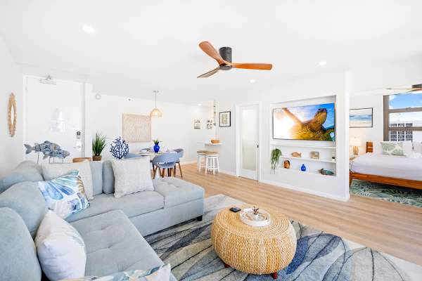The living room features an L-shaped sofa with a pull-out bed, flat-screen TV, ceiling fan, and a coffee table!