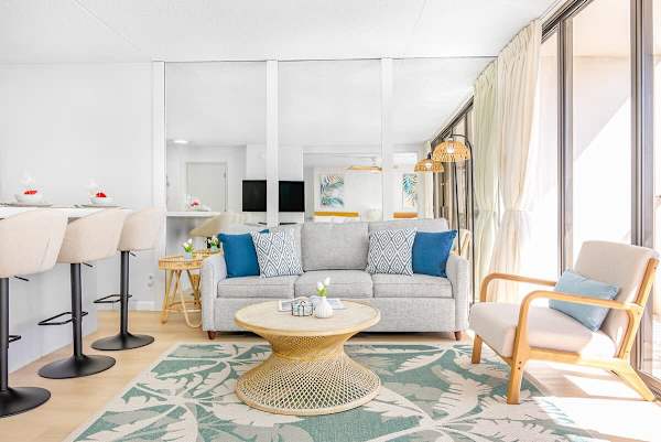 Living room with pull-out sleeper sofa, a coffee table and a chair, and countertop with 4 bar stools.