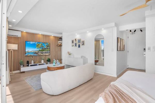A very comfortable living space with a 65'' Samsung Smart TV, full-length mirror, lounge sofa, and lift-top round coffee table.