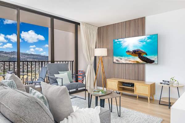 Unwind in a stylish living room with a 65" smart TV and a private balcony offering stunning city and mountain views.